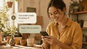 A shop owner smiles at a friendly business text on her phone in a cozy studio.