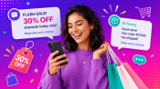 An eCommerce shopper smiling at her phone with shopping bags, receiving SMS promotions from EZ Texting: a flash-sale 30 percent off discount and an order-shipped update.
